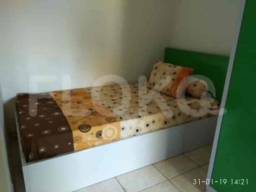 A small bedroom with a single bed and a green headboard.