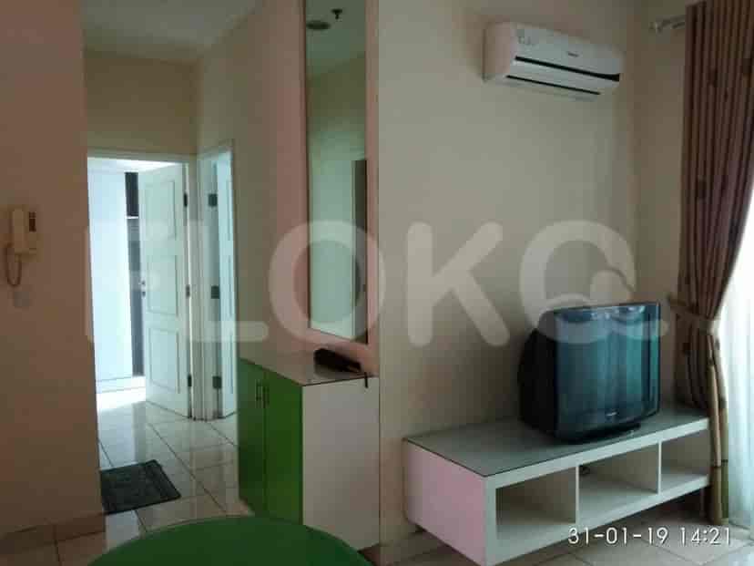 A living area featuring a TV cabinet and a door leading to other rooms.