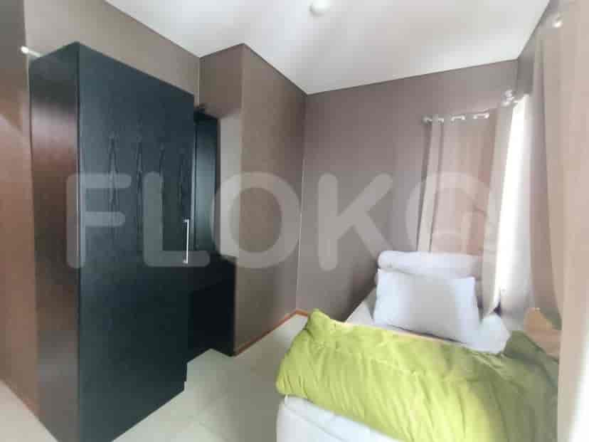 Bedroom with a black wardrobe and bed, along with green bedding and white pillows.