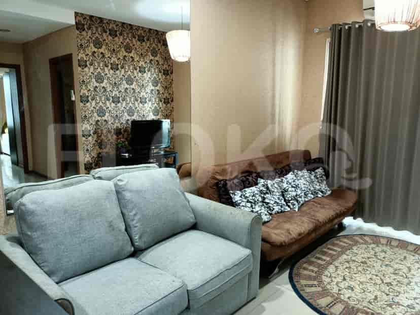 A living room with a sofa and a television set on a table, along with a decorative rug.