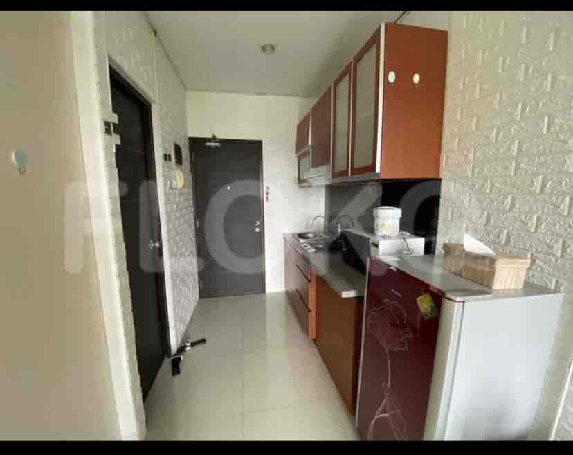 A modern kitchen with brown cabinets, a stainless steel sink, and a refrigerator.