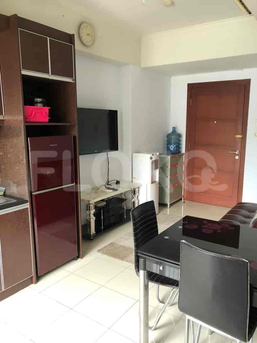 A combined living room and kitchen space with a fridge, TV, and dining table.