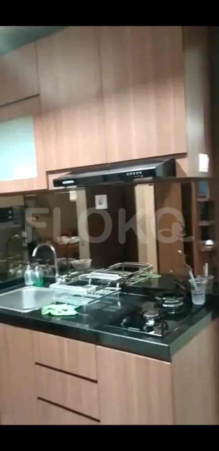 A modern kitchen with light-colored cabinets, a black countertop, and a stove with a chimney.
