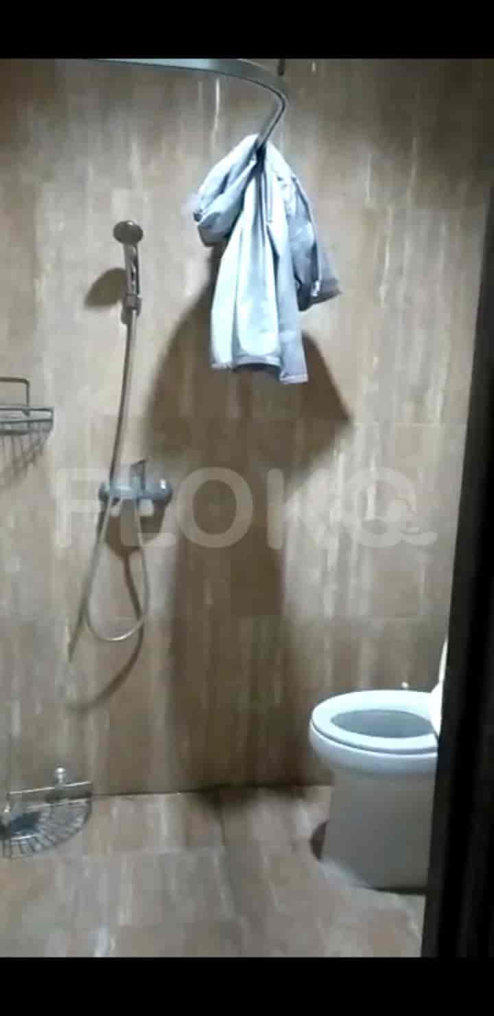 A bathroom with a shower, toilet, and a wall-mounted shelf.