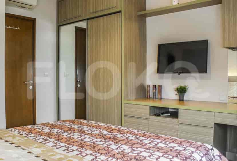 A well-lit bedroom with a bed, a wardrobe, and a wall-mounted TV.