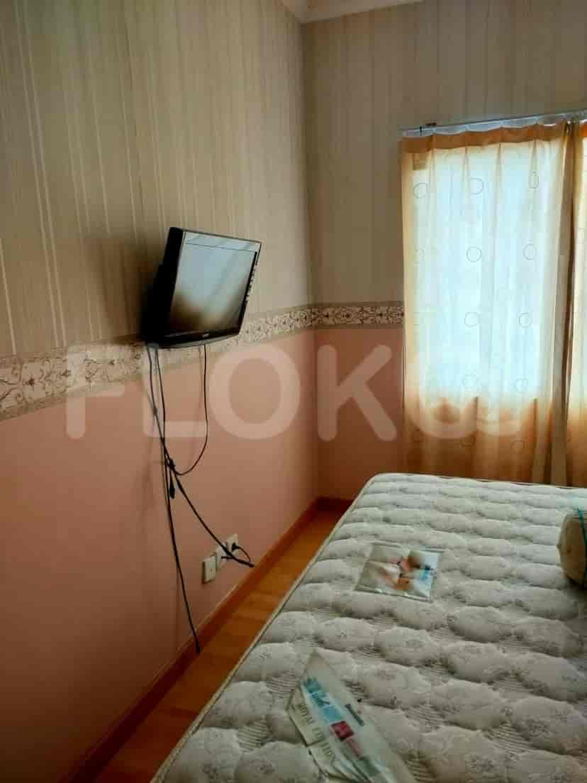 A bedroom with a bed, TV, and beige and pink walls.