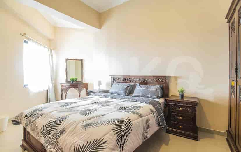 Kamar tidur dengan tempat tidur ukuran king, furnitur kayu, dan sprei bermotif.