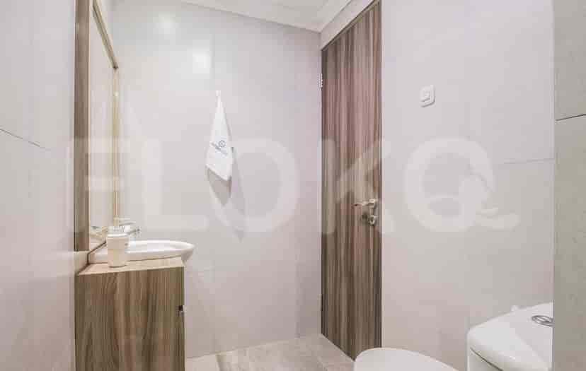 Kamar mandi kompak dengan meja rias kayu, wastafel, dan toilet.