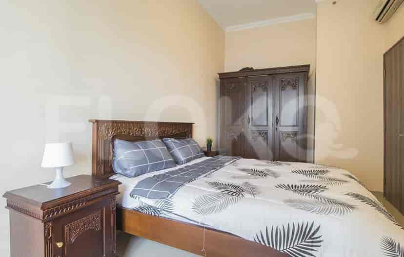 Kamar tidur dengan tempat tidur ganda, furnitur kayu, dan sprei bermotif.