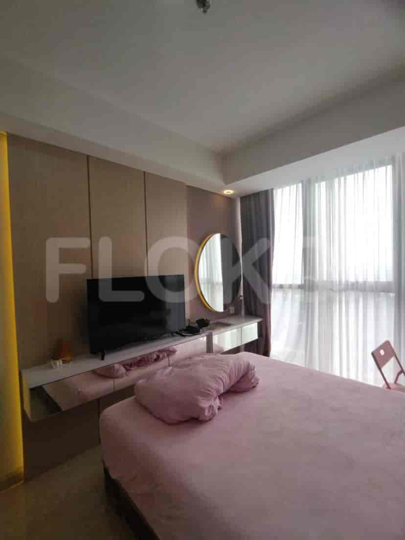 Bedroom with a pink bed, mirrored vanity, and large windows.