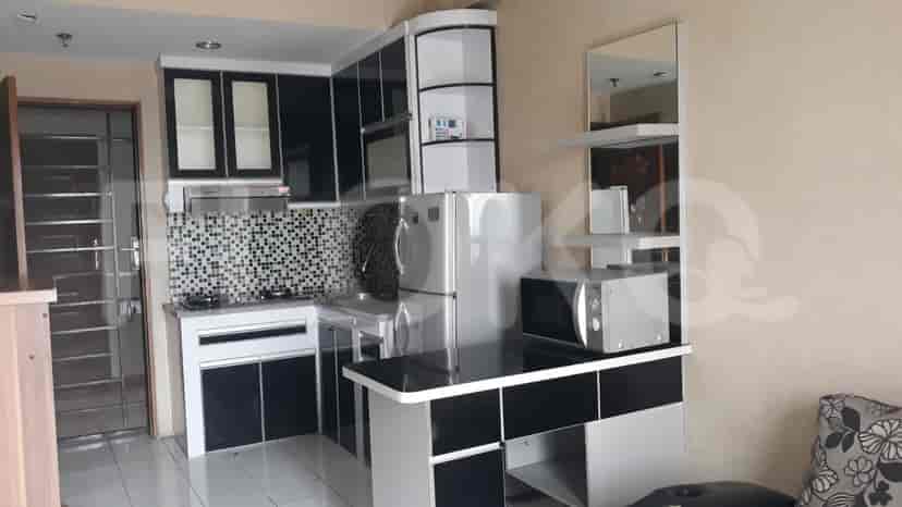 A small kitchen area with modern cabinets, a refrigerator, and a microwave oven.