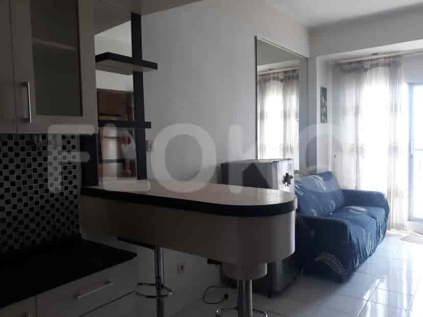 A combined kitchen and living space with a breakfast bar, sofa, and a mirror.