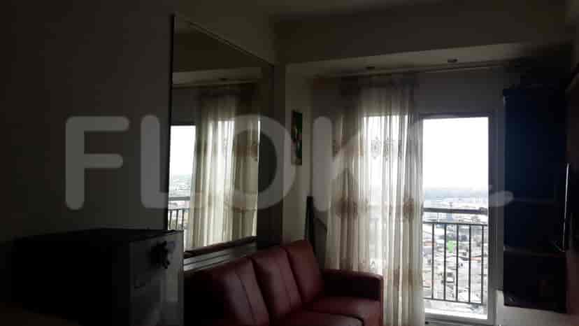 A living room with a red sofa, balcony access, and curtains.