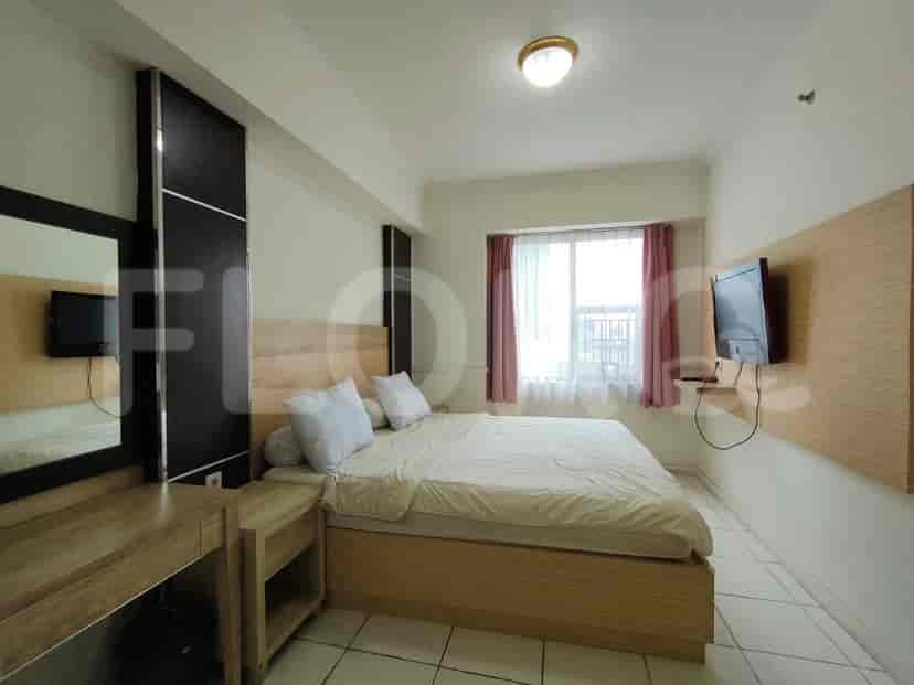 A bright bedroom with a double bed, TV, and a large window.