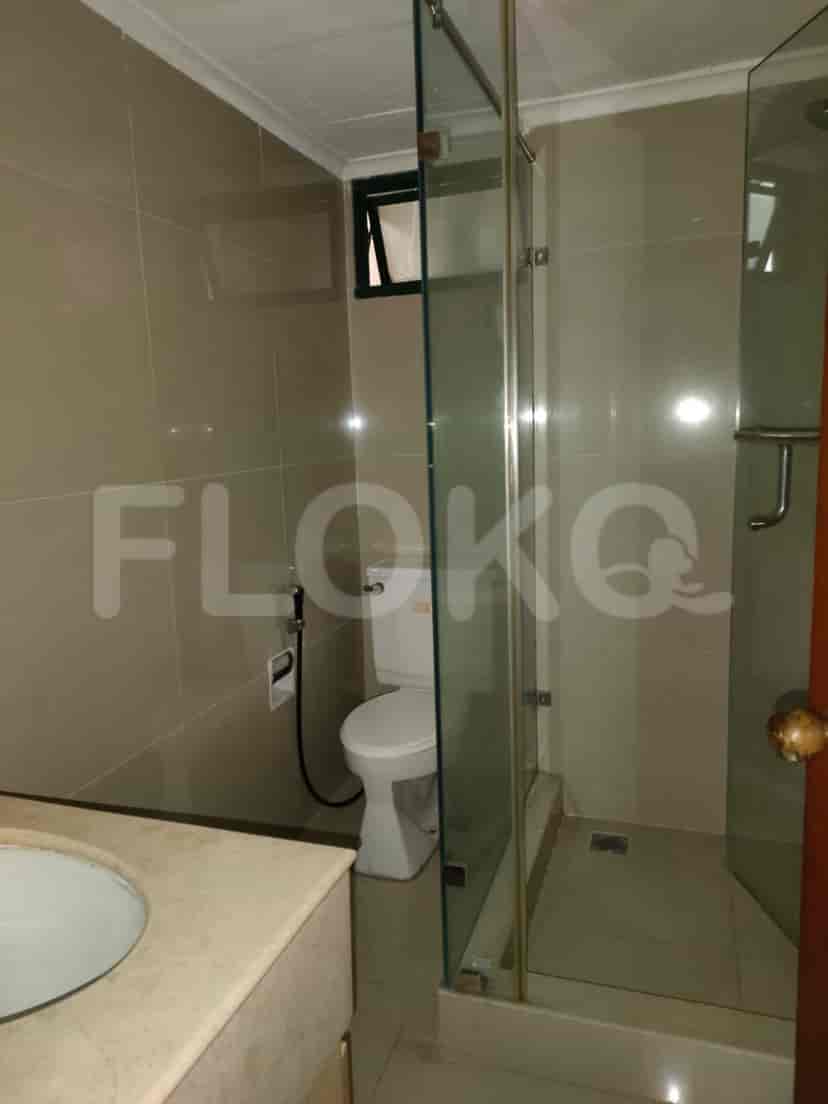 Kamar mandi dengan pancuran kaca dan toilet.