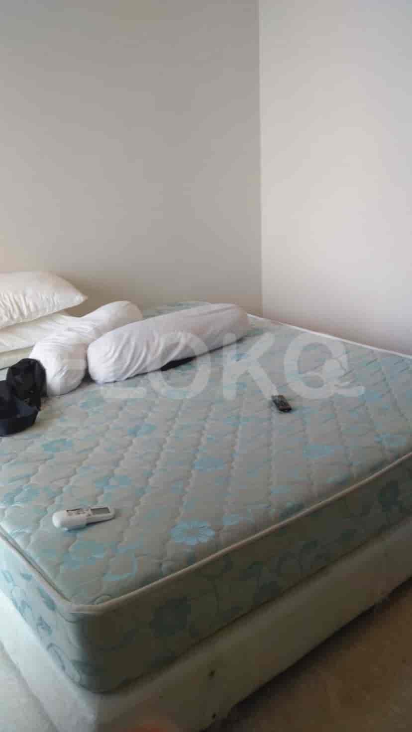 A bedroom with a bed, pillows, and remote control.
