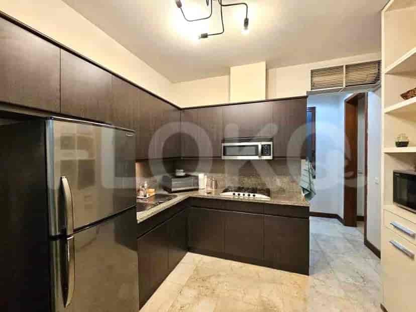 A modern kitchen with dark cabinets, a refrigerator, and a microwave.