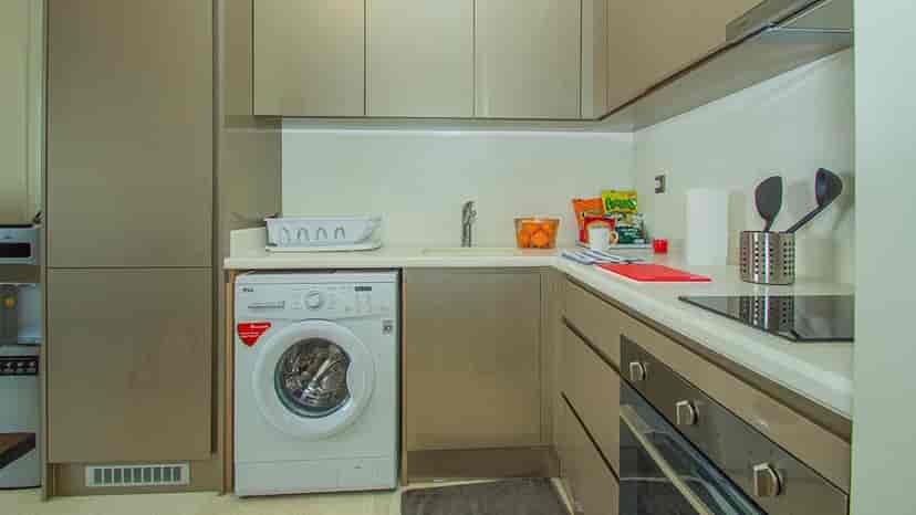 A kitchen with a washing machine and cabinetry.