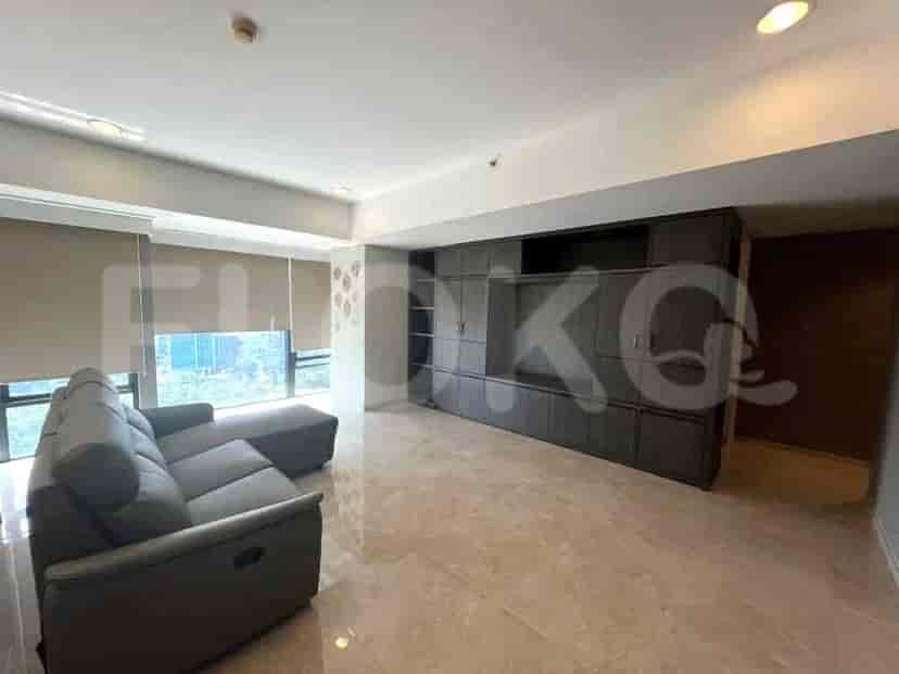 Sebuah ruang tamu luas dengan sofa modular abu-abu, lemari built-in besar, dan jendela dengan tirai.