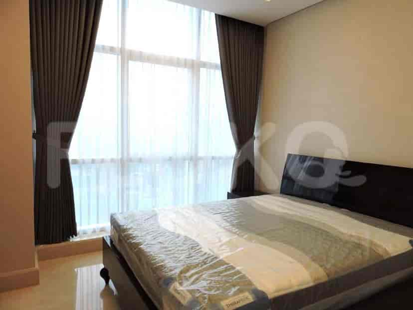 A bedroom with a large bed and a window with curtains.