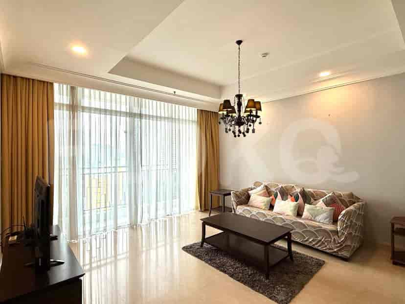 A living room featuring a patterned sofa, coffee table, and a large window with layered curtains.