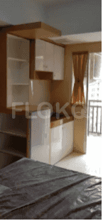 A small kitchen area with white cabinets, a wooden countertop, and a view of the balcony.
