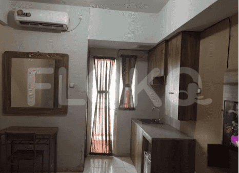 A living area with a kitchenette, wooden mirror, and a small table.