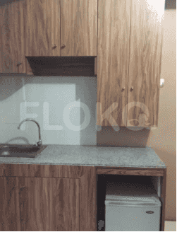 A compact kitchen with wooden cabinets, a stainless steel sink, and a small refrigerator.