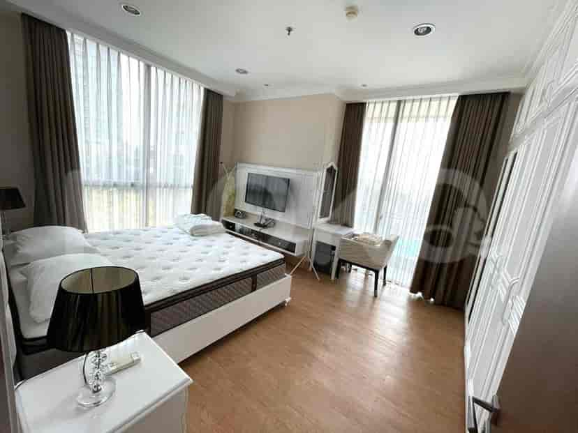 A bedroom with a queen-size bed, a large window with sheer and dark curtains, and a white wardrobe.