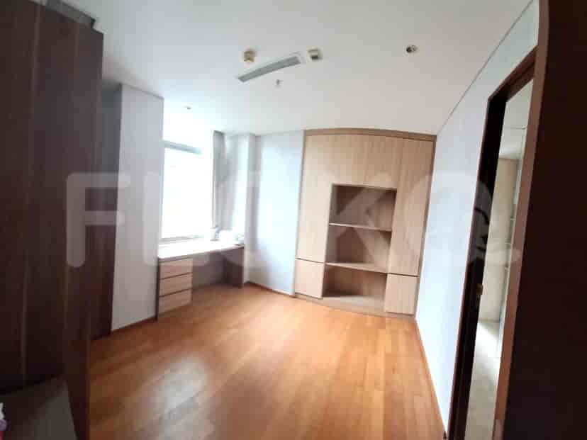 A secondary bedroom with wooden flooring, a desk, and a large built-in wardrobe with shelves.