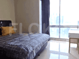 A bedroom with a bed, a large window, and a dressing table.
