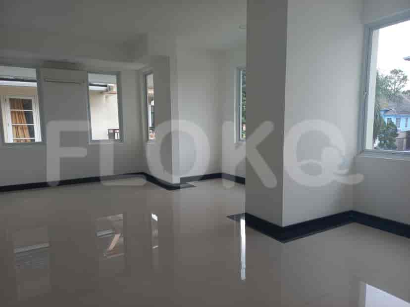 A spacious living area with white walls, tiled flooring, and large windows.