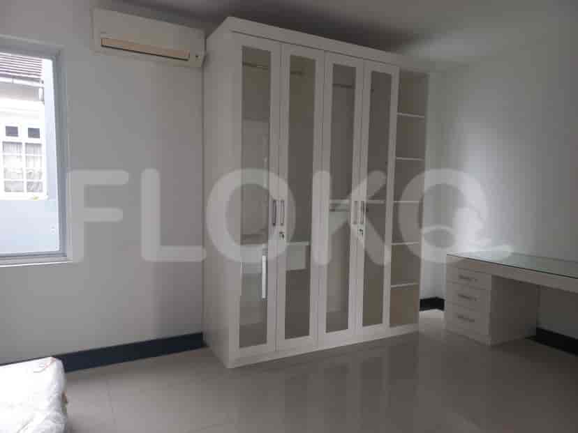 A bedroom with a large wardrobe with glass doors, a desk, and a window.