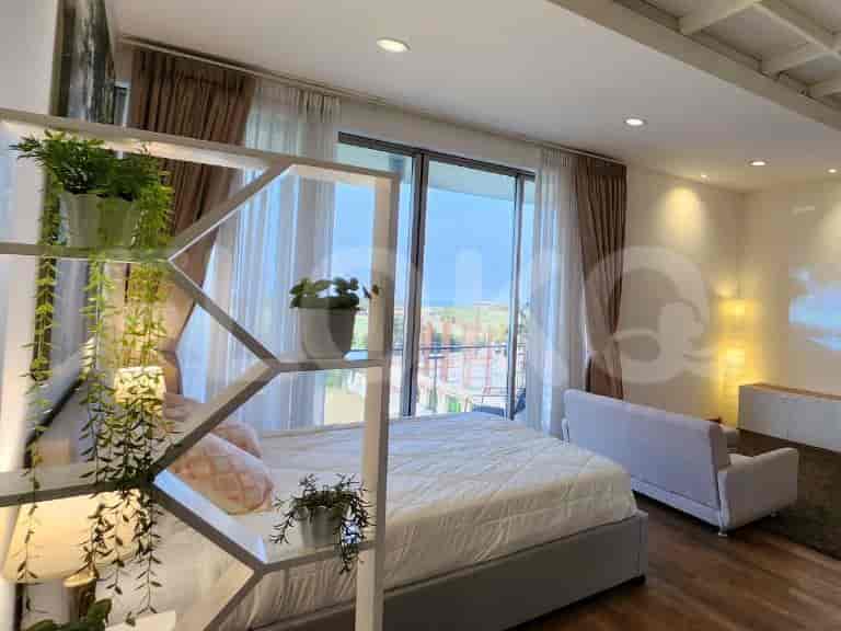 A bedroom with a bed, a sofa, and a view of the ocean through the balcony.