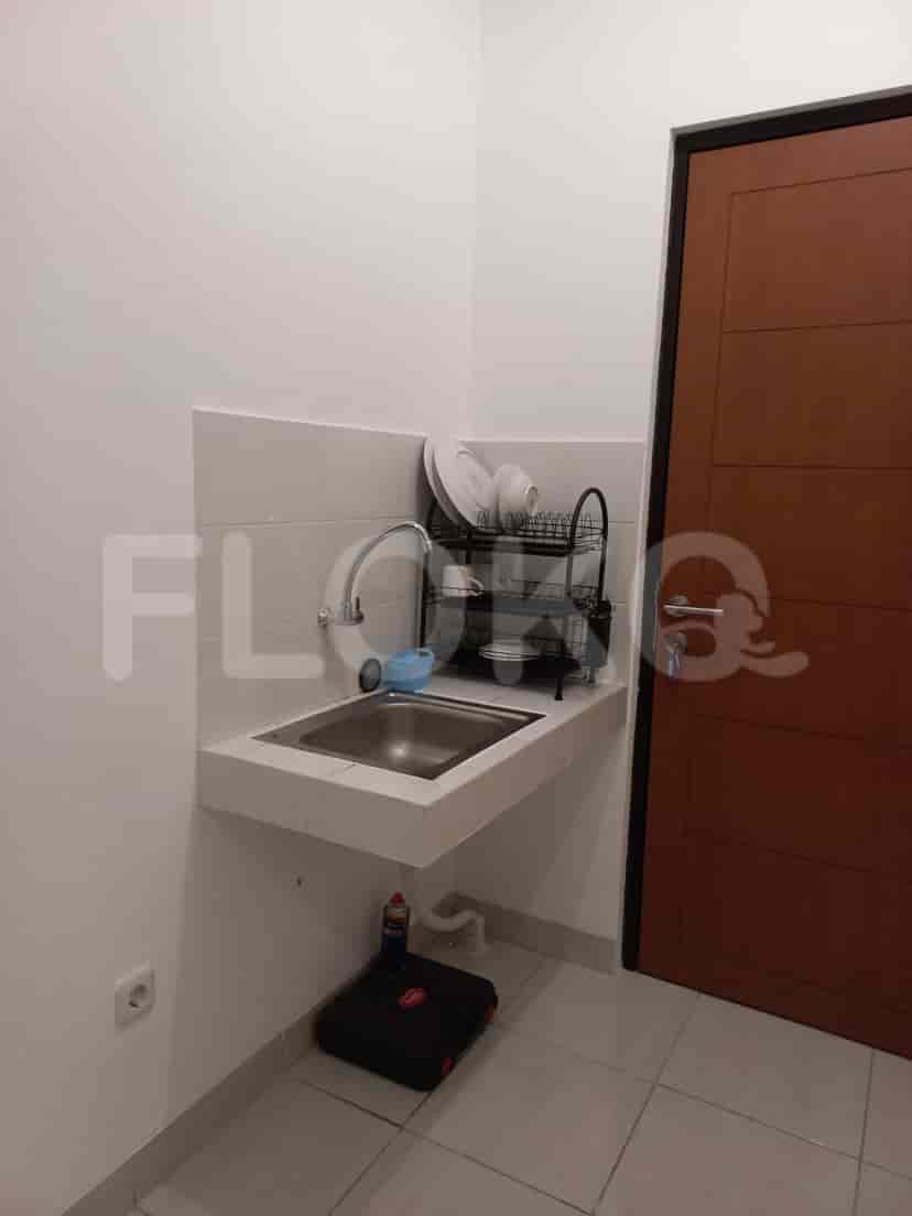 A small kitchenette area with a sink, dish rack, and small countertop.