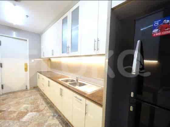 A well-lit kitchen with white cabinets and a black refrigerator.