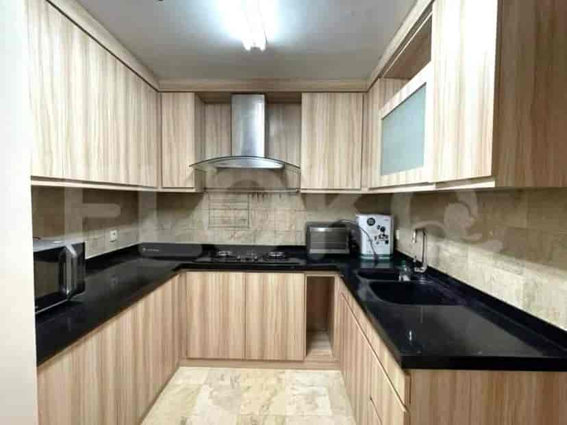 A modern kitchen with light wood cabinets, black countertops, and stainless steel appliances.