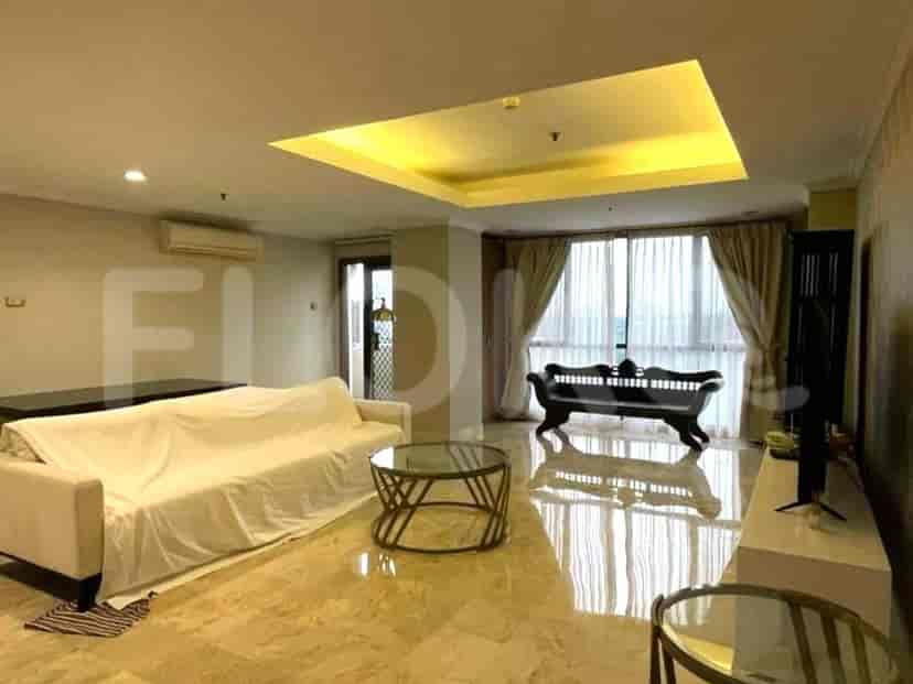 A living room with a white covered sofa, glass coffee table, and a decorative bench.