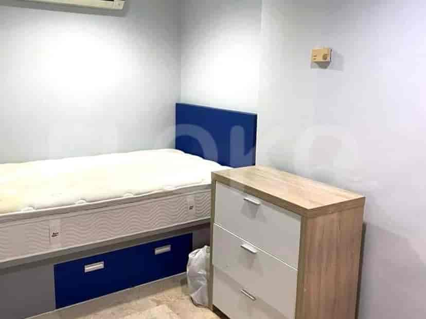 A small bedroom with a single bed, dresser, and blue accent wall.