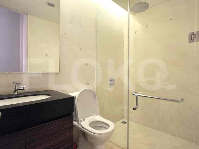 Kamar mandi modern dengan pancuran kaca, toilet, dan wastafel.