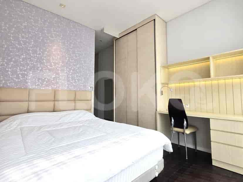 Kamar tidur modern dengan tempat tidur, meja, dan lemari pakaian besar.