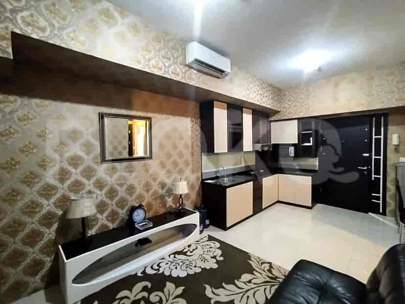 Ruang tamu dan dapur kecil dengan wallpaper bermotif, unit penyimpanan hitam dan putih, dan cermin.