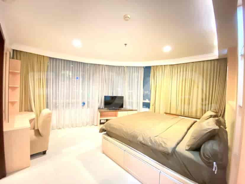 Master bedroom with a bed, desk, and large windows.
