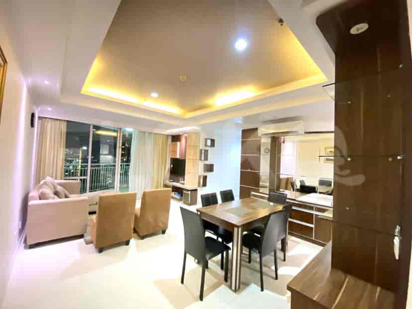 Elegant living room with dining area, featuring a dining table with chairs, a sofa, and a television.