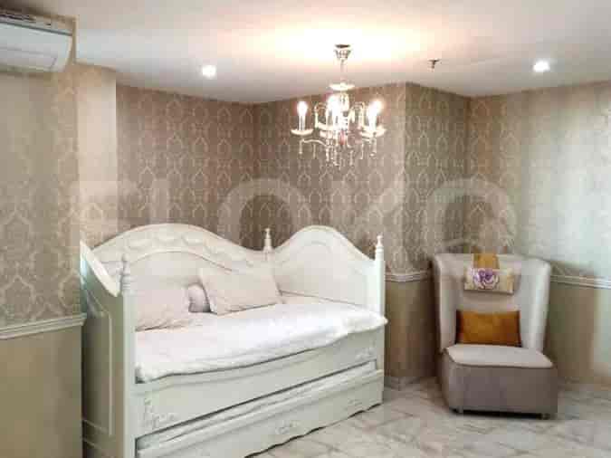 A cozy bedroom with a white daybed, a chair, and a chandelier.