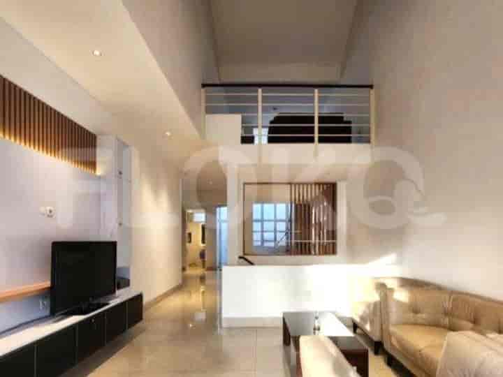 A modern living area with a double-height ceiling, a mezzanine, and a wall-mounted TV.