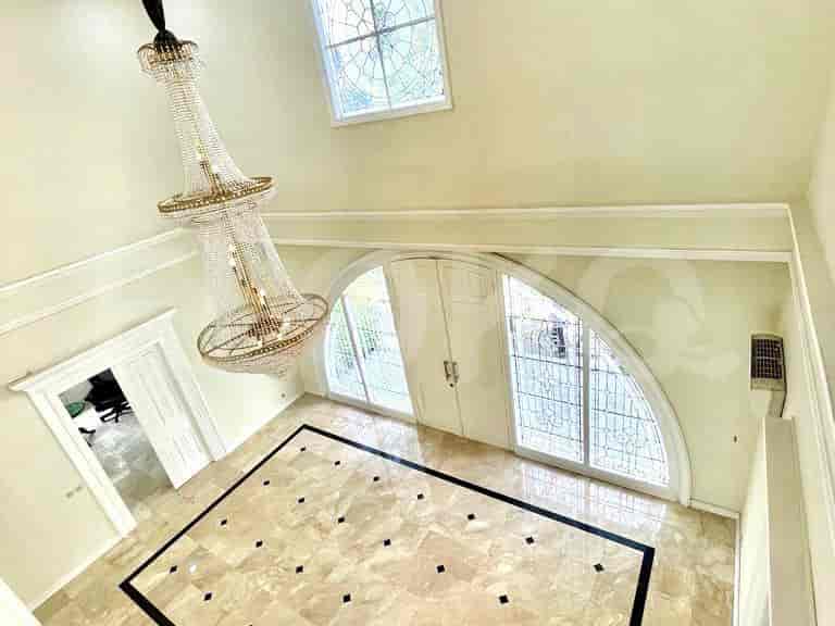 High-angle view of an entryway with marble flooring, a grand chandelier, and arched doorways.