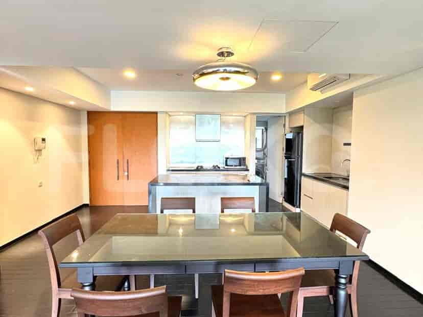 Area dapur dan ruang makan terbuka dengan meja makan yang diatur untuk makan, dapur menampilkan pulau dengan pencahayaan di atas kepala dan desain modern.