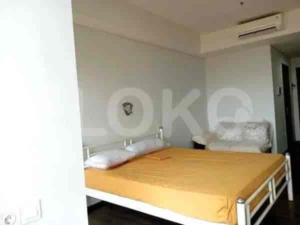 Kamar tidur dengan rangka tempat tidur logam putih, sprei kuning, dan sofa putih kecil.
