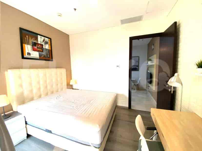 Kamar tidur dengan tempat tidur, meja, dan pemandangan langit kota.